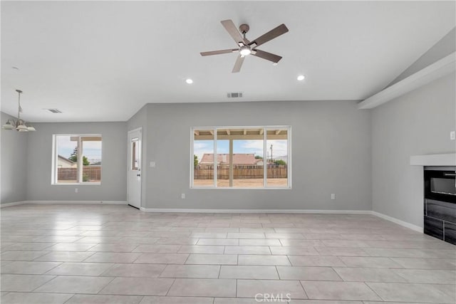 unfurnished living room with a wealth of natural light, light tile patterned flooring, ceiling fan with notable chandelier, and vaulted ceiling