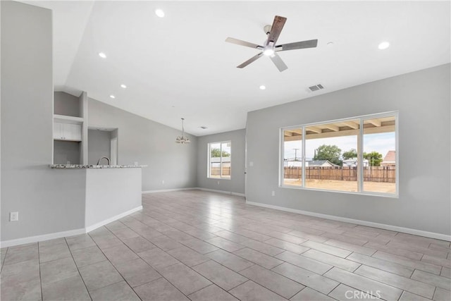 unfurnished living room with ceiling fan with notable chandelier and vaulted ceiling