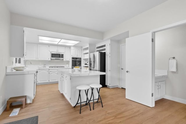 kitchen featuring a center island, light wood-type flooring, white cabinetry, and appliances with stainless steel finishes