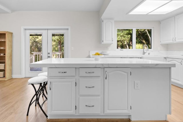 kitchen featuring a healthy amount of sunlight, a kitchen island, and white cabinetry