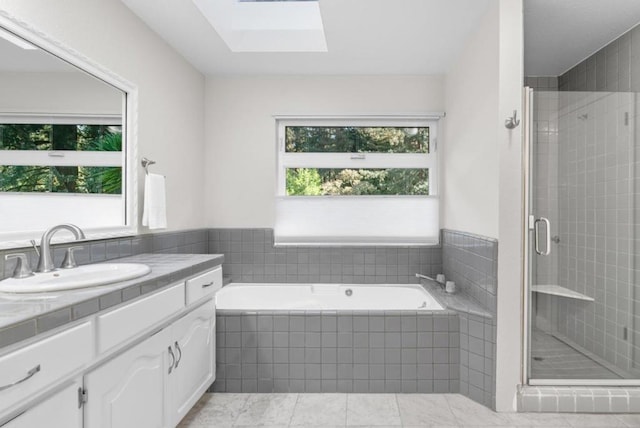 bathroom with tile patterned floors, vanity, separate shower and tub, and a skylight