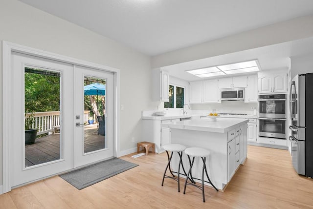 kitchen with a wealth of natural light, a center island, appliances with stainless steel finishes, and french doors