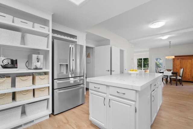 kitchen with stainless steel fridge, light hardwood / wood-style flooring, and white cabinetry