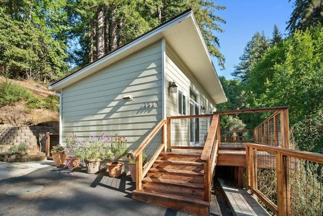 view of side of home with a wooden deck and a patio