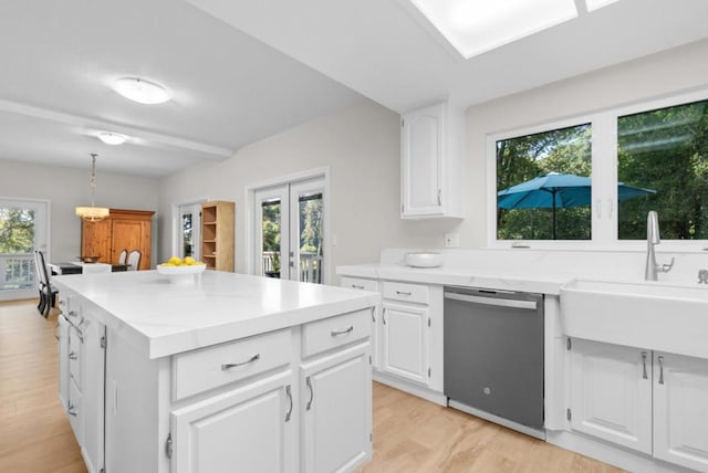 kitchen with sink, white cabinetry, stainless steel dishwasher, and light hardwood / wood-style flooring