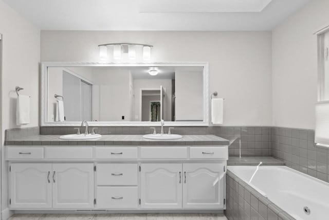 bathroom featuring vanity and tiled bath