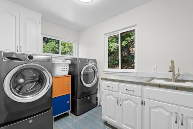 clothes washing area featuring washer and clothes dryer, plenty of natural light, cabinets, and sink