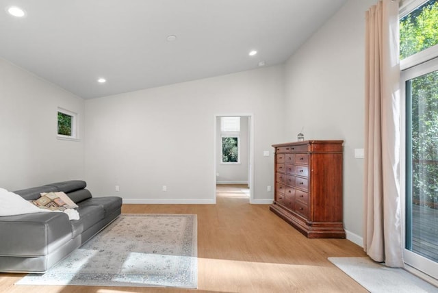 living room with a healthy amount of sunlight, light wood-type flooring, and lofted ceiling