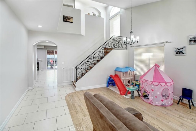 rec room featuring radiator heating unit, light wood-type flooring, and a notable chandelier