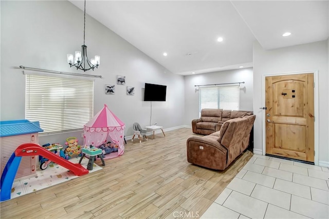 rec room with a chandelier, high vaulted ceiling, and light hardwood / wood-style floors