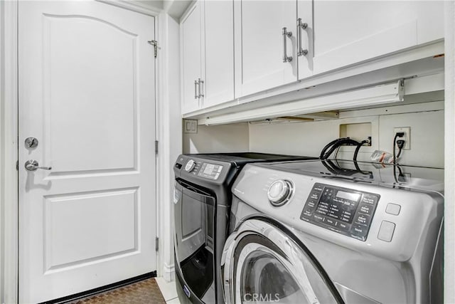 laundry room featuring washer and clothes dryer and cabinets