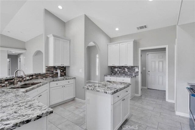 kitchen featuring white cabinetry, sink, and light stone countertops