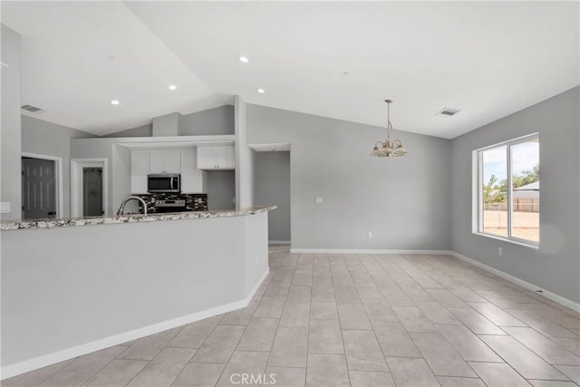 kitchen featuring lofted ceiling, decorative light fixtures, a notable chandelier, light stone counters, and white cabinetry