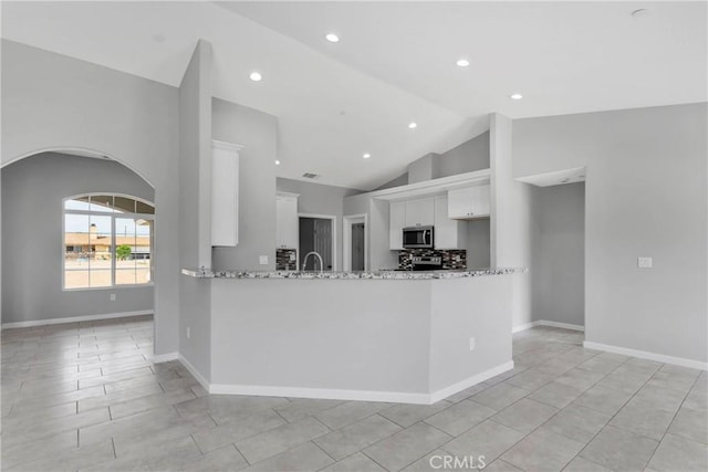 kitchen featuring light stone countertops, kitchen peninsula, light tile patterned floors, high vaulted ceiling, and white cabinetry