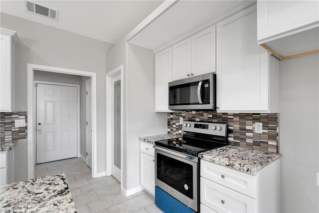 kitchen featuring backsplash, light tile patterned floors, light stone countertops, appliances with stainless steel finishes, and white cabinetry