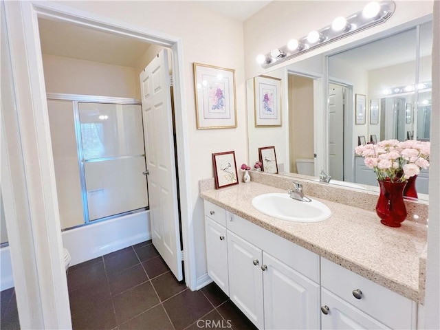 full bathroom featuring tile patterned floors, combined bath / shower with glass door, toilet, and vanity