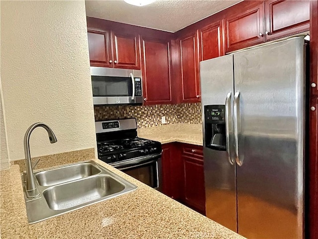 kitchen with a textured ceiling, sink, stainless steel appliances, and tasteful backsplash