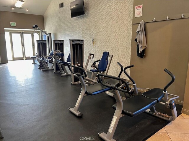 gym featuring light tile patterned flooring and high vaulted ceiling