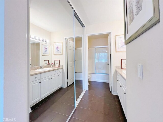 full bathroom featuring tile patterned flooring, vanity, enclosed tub / shower combo, and toilet