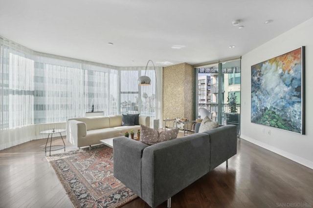 living room with floor to ceiling windows, a healthy amount of sunlight, and dark hardwood / wood-style flooring