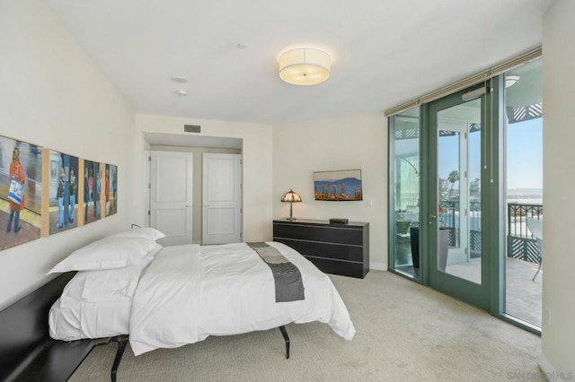 bedroom with light colored carpet, access to exterior, and a wall of windows