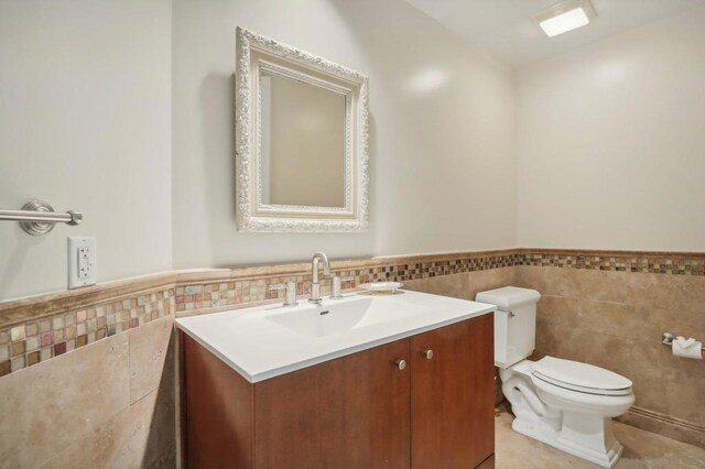 bathroom with tile patterned floors, vanity, toilet, and tile walls