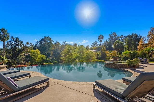 view of pool with a patio area, an in ground hot tub, and a water view