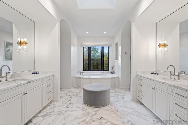 bathroom featuring a bathing tub, vanity, and a skylight