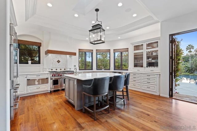 kitchen with high end range, white cabinets, premium range hood, and hanging light fixtures