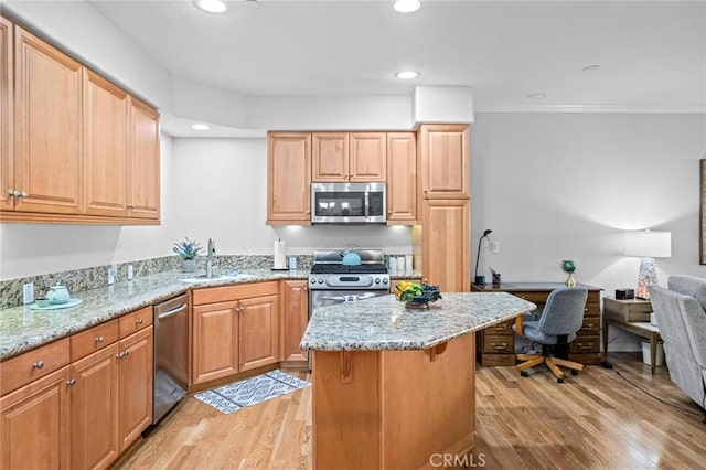 kitchen featuring a breakfast bar, sink, light wood-type flooring, appliances with stainless steel finishes, and light stone counters