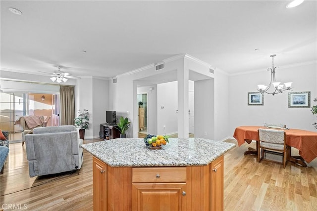 kitchen with a center island, crown molding, hanging light fixtures, and light hardwood / wood-style flooring