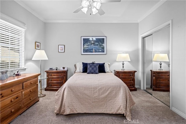 carpeted bedroom featuring ceiling fan, a closet, and crown molding