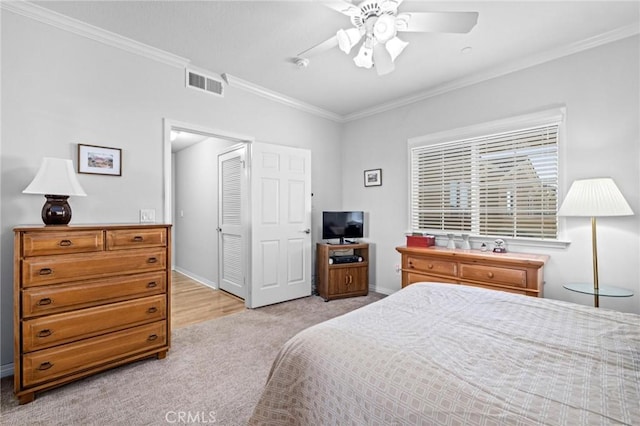 carpeted bedroom with ceiling fan, ornamental molding, and a closet