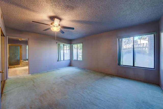 carpeted empty room with ceiling fan and a textured ceiling