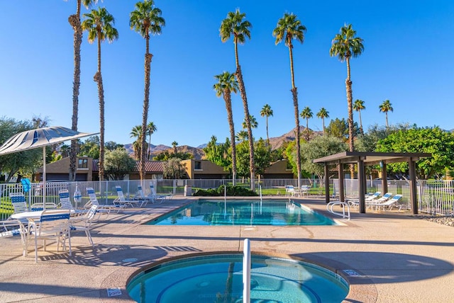 view of swimming pool featuring a community hot tub, a patio area, and a mountain view