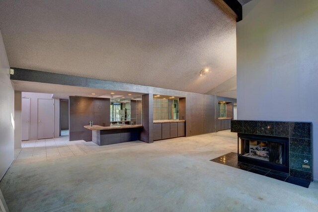 living room featuring lofted ceiling, carpet floors, and a tile fireplace