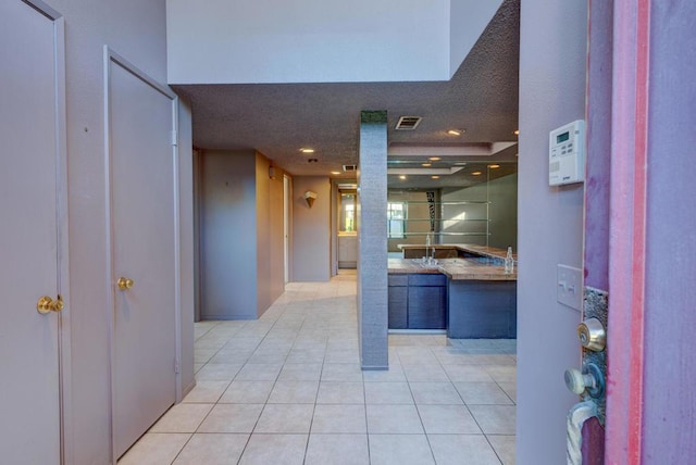 hallway featuring light tile patterned floors and a textured ceiling