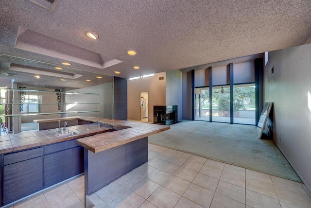 kitchen with a wealth of natural light, tile countertops, light colored carpet, and sink