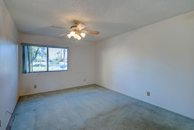 carpeted spare room featuring ceiling fan and a textured ceiling