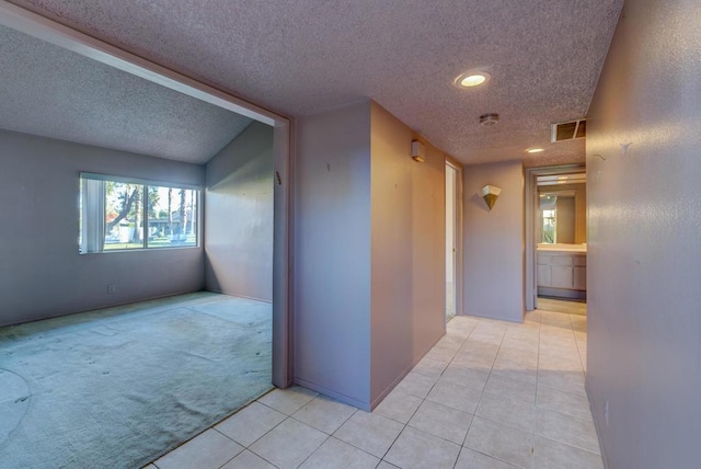 corridor featuring light tile patterned floors and a textured ceiling