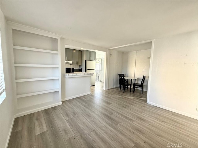 unfurnished living room featuring hardwood / wood-style floors and built in features