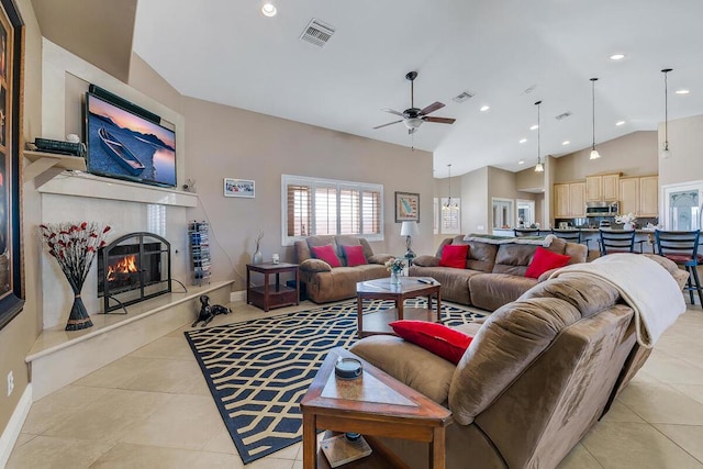 tiled living room featuring ceiling fan, a tiled fireplace, and high vaulted ceiling