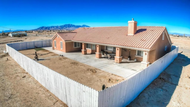 back of property with a mountain view and a patio