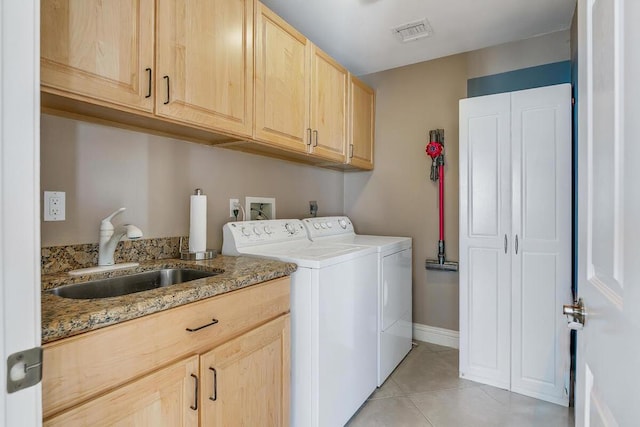 clothes washing area with cabinets, sink, light tile patterned floors, and independent washer and dryer