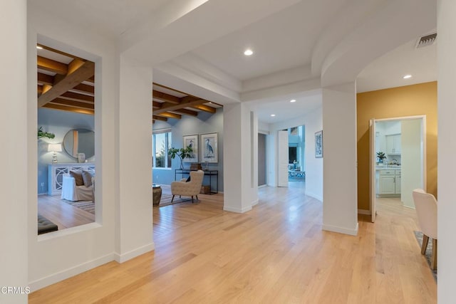 corridor with beam ceiling and light hardwood / wood-style flooring