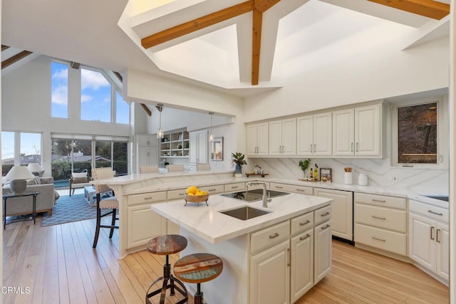 kitchen featuring a center island with sink, a kitchen breakfast bar, light wood-type flooring, and high vaulted ceiling