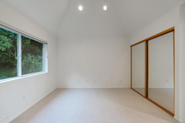 unfurnished bedroom with vaulted ceiling, carpet floors, a closet, and multiple windows