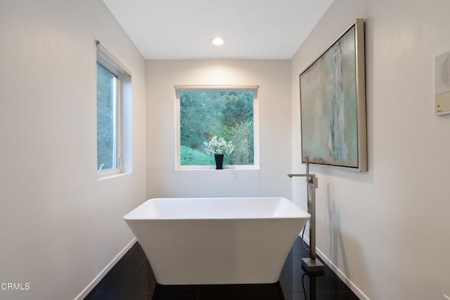 bathroom with a washtub and tile patterned flooring