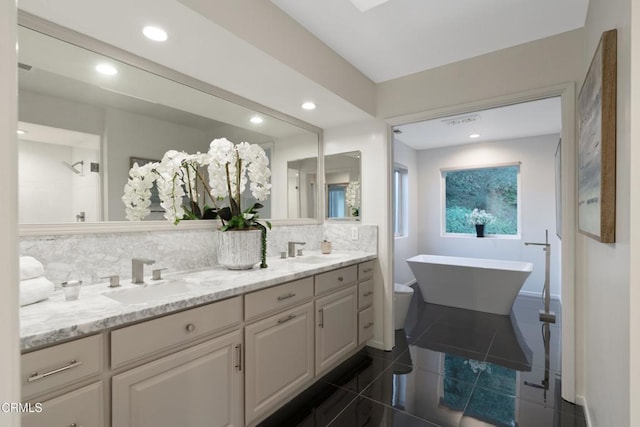 bathroom featuring backsplash, tile patterned floors, vanity, a bath, and toilet