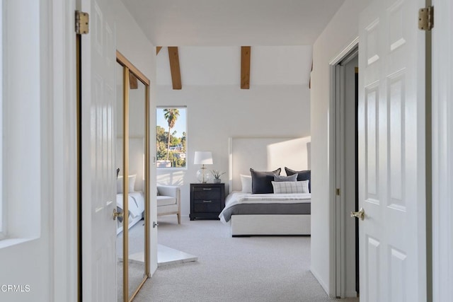 bedroom featuring beam ceiling, light colored carpet, and a closet